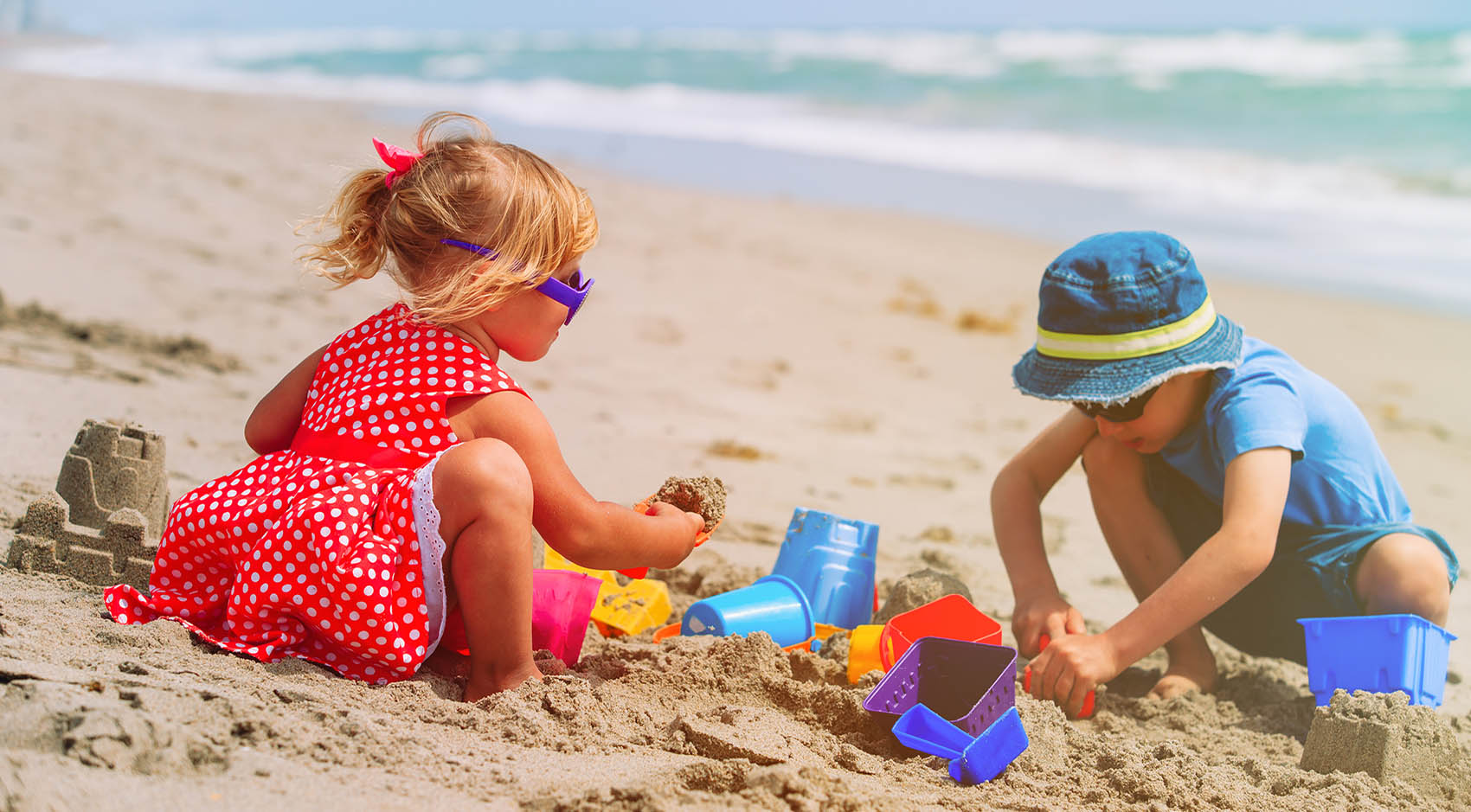 little boy and girl building sand castle on the beach 